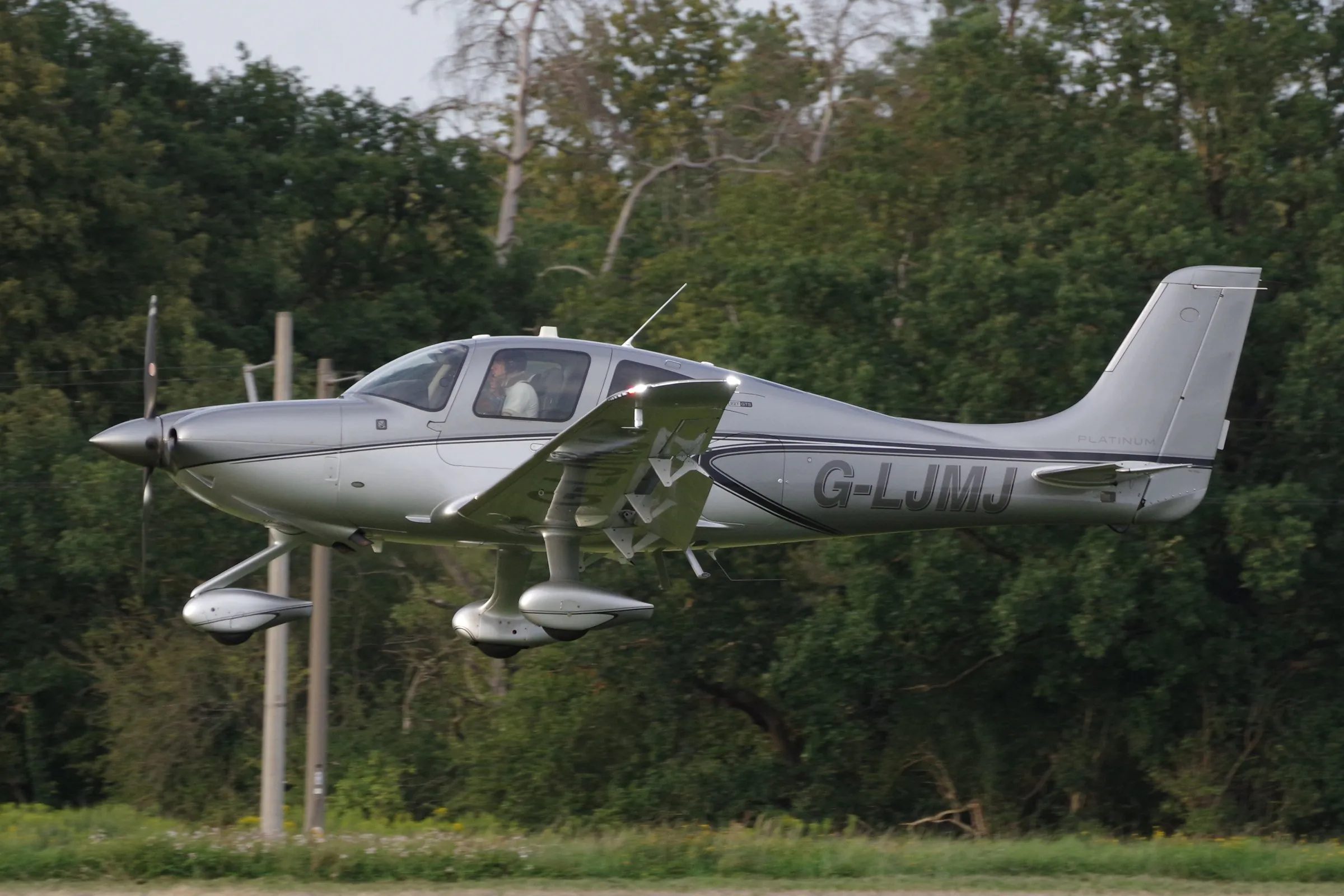 Cirrus SR22T G6 em voo baixo diante de árvores